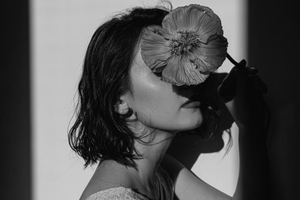 Portrait de femme cachant son viszge avec une fleur comme pour évoquer une gène physique